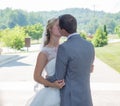 Just-married couple kissing in a garden surrounded by hills and greenery under the sunlight Royalty Free Stock Photo