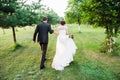 Just married couple running away in a green summer garden Royalty Free Stock Photo