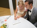 Just-married couple signing a prenup paper on a white table under the lights