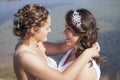 Just married happy lesbian couple in white dress near small lake