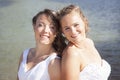 just married happy lesbian couple in white dress pose close together near small lake