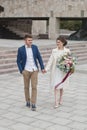 Just married loving couple in wedding dress and suit . Happy bride and groom walking running in the summer city. Royalty Free Stock Photo