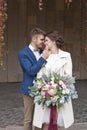 Just married loving couple in wedding dress and suit outdoor in city setting against wall. Happy bride and groom laughing