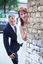 Just married people peek around corner of brick wall Royalty Free Stock Photo