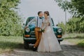 Just married wedding couple is standing near the retro vintage car in the park. Summer sunny day in forest. bride in Royalty Free Stock Photo