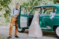 Just married wedding couple is standing near the retro vintage car in the park. Summer sunny day in forest. bride in Royalty Free Stock Photo