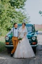 Just married wedding couple is standing near the retro vintage car in the park. Summer sunny day in forest. bride in Royalty Free Stock Photo