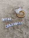 Just married written on sand at the beach with two beautiful gold and silver wedding rings Royalty Free Stock Photo