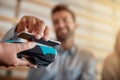 Just one tap and your transaction is complete. a man making a payment with his cellphone using NFC technology in a cafe.