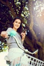 Just out for a leisurely ride. Portrait of an attractive young woman using her cellphone while riding her bicycle. Royalty Free Stock Photo