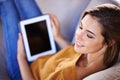 Just passing the time. an attractive young woman relaxing on the sofa with her tablet.