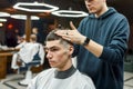 Just perfect. Professional barber making hair styling for a young and handsome guy while working in the modern