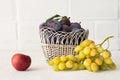 Just picked plums and grapes in wicker basket on white backdrop Royalty Free Stock Photo