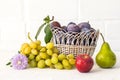 Just picked plums and grapes in wicker basket on white backdrop Royalty Free Stock Photo