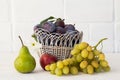 Just picked plums, pear and grapes in wicker basket on white backdrop Royalty Free Stock Photo