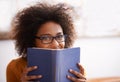 Just a quick peek and then its back to reading. Portrait of an attractive young woman peering over the book shes reading Royalty Free Stock Photo