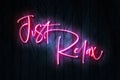 Just Relax pink neon sign on a Dark Wooden Wall 3D illustration