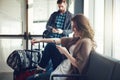 Just saying goodbye to the family. a young couple sitting in an airport with their luggage while making use of their Royalty Free Stock Photo