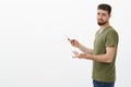 Just sec, can you see I busy. Portrait of irritated cute boyfriend gamer standing in profile with smartphone turning at