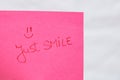 Just smile handwriting text close up isolated on pink paper with copy space. Writing text on memo post reminder