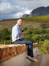 Just taking it easy. Portrait of a mature man sitting on wall and enjoying a glass of red wine. Royalty Free Stock Photo