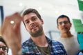 He just thought of something great. a group of designers brainstorming with notes on a glass wall in an office.