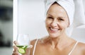 Just try it, it works. a mature woman holding a glass of water with cucumber in. Royalty Free Stock Photo