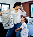 Just wait honey, Im on the phone. a young attractive mother doing laundry with her son at home. Royalty Free Stock Photo