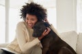 He just wants to cuddle. an attractive young woman petting her dog while sitting on the sofa at home.