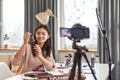 Just What You Need. Asian female blogger showing cosmetic products while recording a tutorial video for her beauty blog Royalty Free Stock Photo