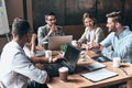 Just working day. Top view of young modern people in smart casual wear discussing business while sitting in the creative office