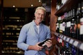 Just the year I was looking for. Portrait of a handsome mature man buying wine at a grocery store. Royalty Free Stock Photo