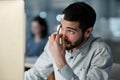 Just when you thought you could clock out. Shot of a young man feeling stressed while using a headset and computer late Royalty Free Stock Photo