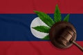 Justice wooden gavel with cannabis leaf on the Flag of Laos. Illegal growth of cannabis plant and drugs spreading