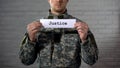 Justice word written on sign in hands of male soldier, military court, tribunal Royalty Free Stock Photo