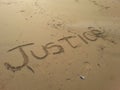 Justice written on beach sand.