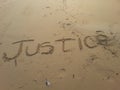 Justice written on beach sand.