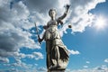 Justitia symbol of justice in front of background with sky and c