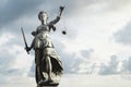Justitia symbol of justice in front of background with sky and c