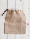 Jute hessian canvas tote bag with drawstring, mockup of small eco sack made from natural hemp burlap flat lay on white wood