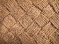 Jute rug close-up. The jute weave is close. A fragment of a large weaving with a rhombus, background, texture. Royalty Free Stock Photo