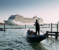 Juxtaposition of gondola and huge cruise ship in Giudecca Canal. Old and new transportation on the Venice Lagoon