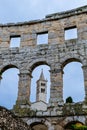 More modern church steeple seen through the ancient Pula Arena arch Royalty Free Stock Photo