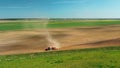 4K Aerial View Tractor With Seed Drill Machine Sowing The Seeds For Crops In Spring Season. Beginning Of Agricultural