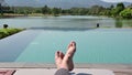 4K Bare feet of young man lying on deck chair sunbathing by the swimming pool