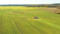 4K Elevated View Of Combine Harvester Tractor In Field. Harvesting Of Oilseed In Spring. Agricultural Machines