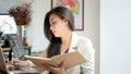 4K footage, beautiful Asian business woman sitting with computer laptop keying data, reading and flip over note book page