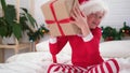 Little boy shakes gift box to find out what is inside. Child in Christmas Santa hat and pajama. Fulfilling children