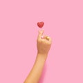 K pop concept. A girl teenager hand with two heart shape rings showing finger heart gesture. Red glitter heart above. Minimal baby Royalty Free Stock Photo
