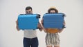 4k slow-motion video of man and woman hiding behind blue suitcases.